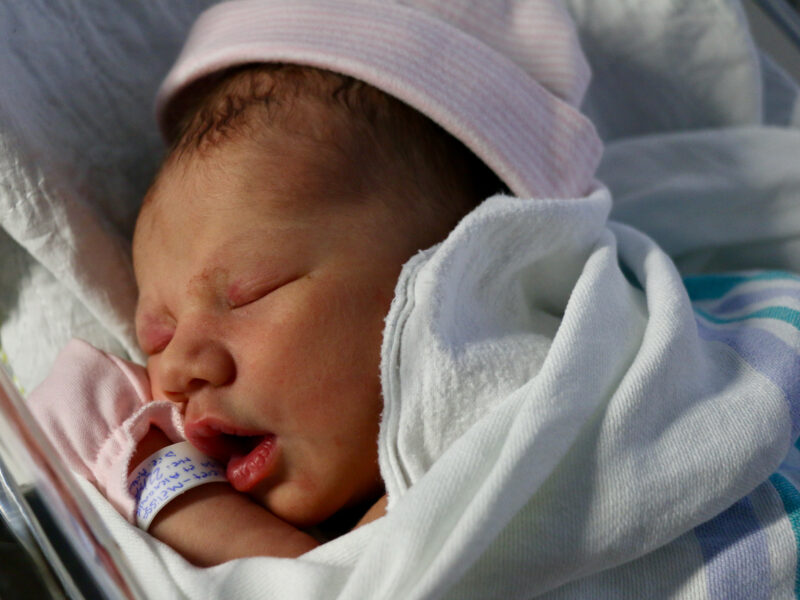 Newborn baby sleeping with beanie and blanket